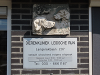 850580 Afbeelding van een reliëf met drie hondenkoppen boven het informatiebord van Dierenkliniek Leidsche Rijn ...